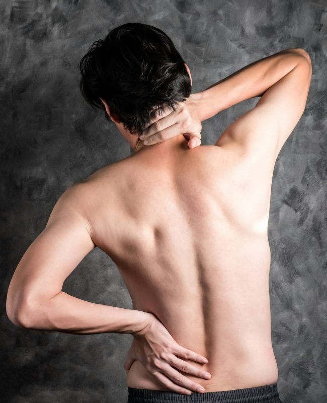 a man with back pain on grey background